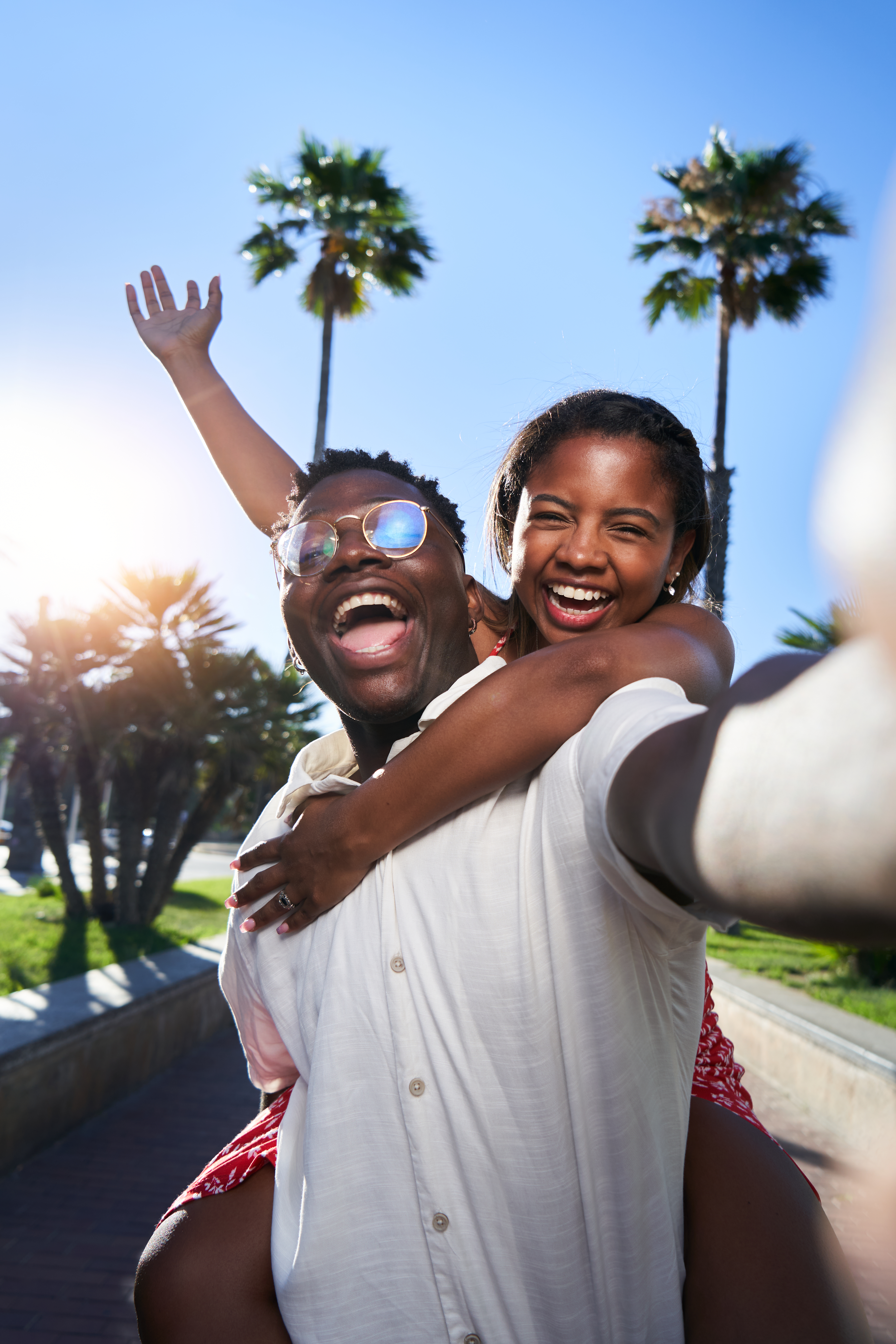 A young Black couple taking a cheerful selfie while traveling
